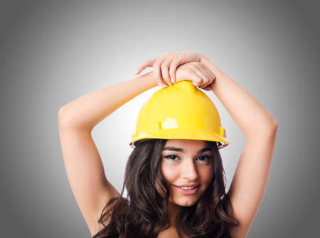 Young woman with hellow hard hat against gradientの写真素材
