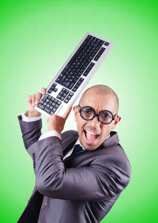 Nerd businessman with computer keyboard against gradientの写真素材