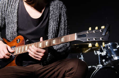 Man playing guitar in dark room
