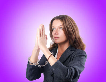 Female businesswoman with handcuffs against gradientの写真素材