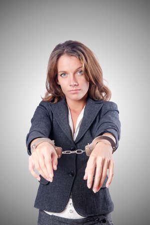 Female businesswoman with handcuffs against gradientの写真素材
