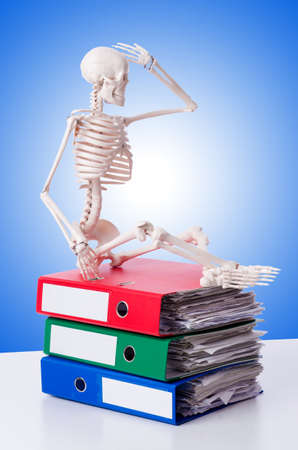 Skeleton with pile of files against gradientの写真素材