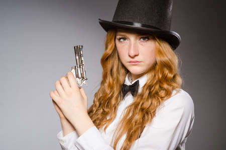 Pretty girl wearing retro hat and holding weapon isolated on grayの写真素材