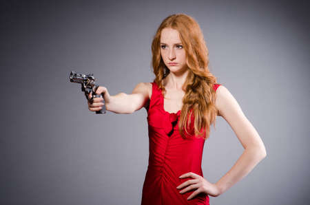 Pretty young girl in red dress with gun isolated on whiteの写真素材