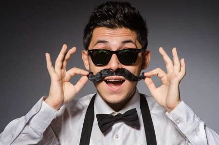 Young man with false moustache isolated on grayの写真素材