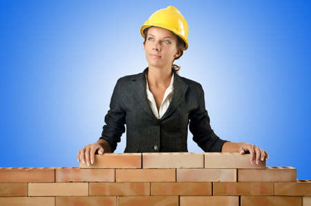 Young female builder near brick wallの写真素材