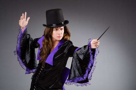 Pretty magician girl holding stick against grayの写真素材