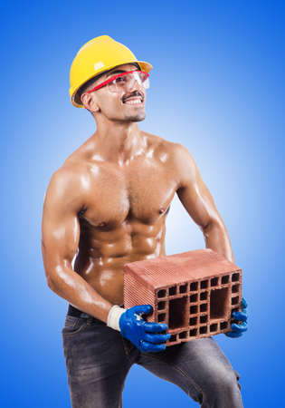 Muscular builder with bricks on whiteの写真素材