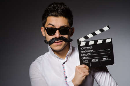 Young caucasian man with clapperboard against grayの写真素材