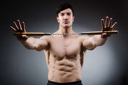 Muscular strong man with nunchucksの写真素材