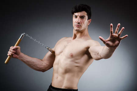 Muscular strong man with nunchucksの写真素材