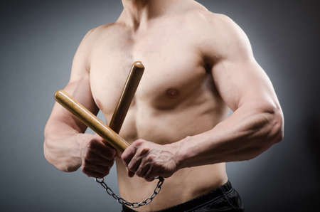Muscular strong man with nunchucksの写真素材