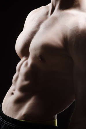 Muscular man posing in dark studio