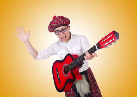 Funny scotsman with guitar on whiteの写真素材