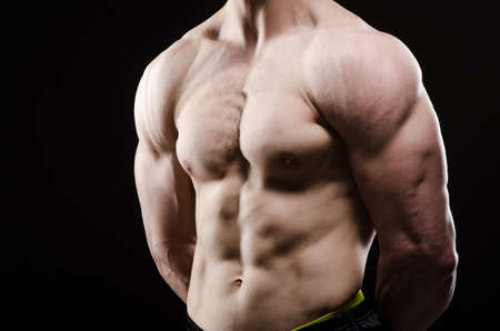 Muscular man posing in dark studio