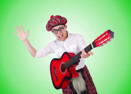 Funny scotsman with guitar on whiteの写真素材