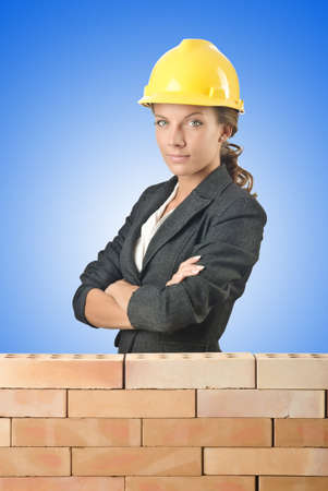 Young female builder near brick wallの写真素材