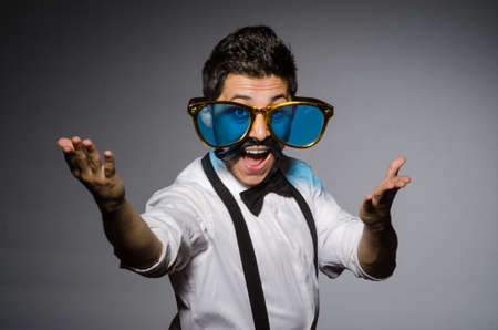 Young caucasian man wearing sunglasses against gray