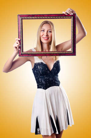 Young woman with picture frame on whiteの写真素材