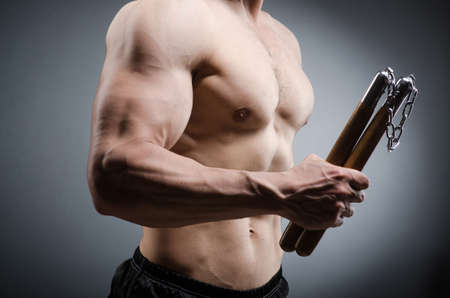 Muscular strong man with nunchucksの写真素材
