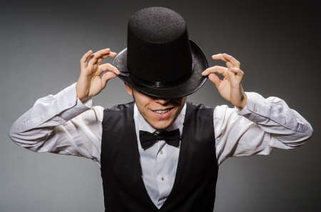 Young man in classical black vest and hat against grayの写真素材