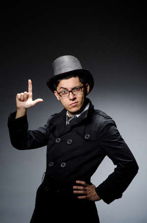 Young man in black coat and hat against grayの写真素材