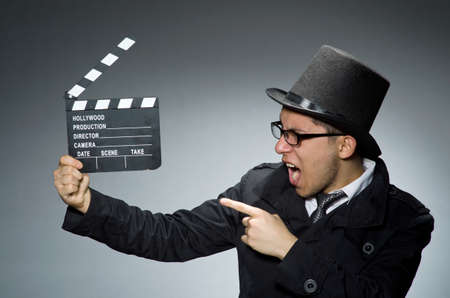 Detective in black coat with clapperboard against grayの写真素材