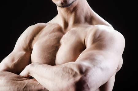 Muscular man posing in dark studio