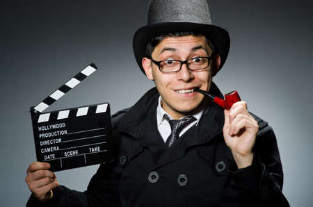 Detective in black coat with clapperboard against grayの写真素材