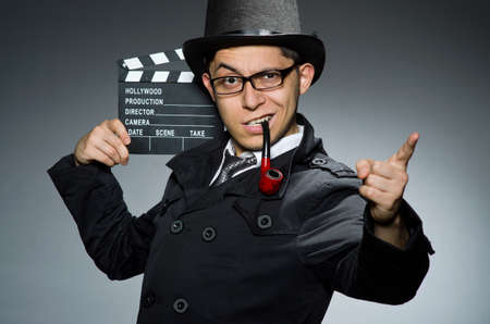 Detective in black coat with clapperboard against grayの写真素材