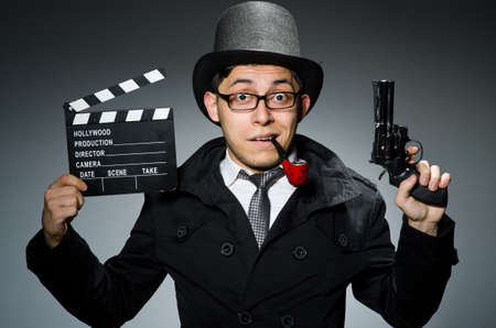 Detective in black coat with clapperboard against grayの写真素材