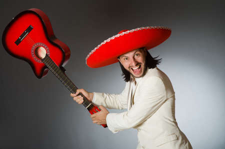 Funny mexican in suit holding guitar against grayの写真素材