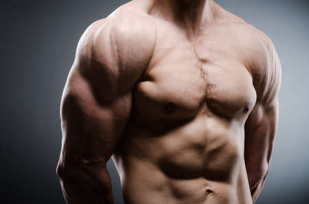 Muscular man posing in dark studio