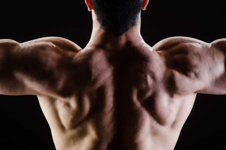 Muscular man posing in dark studio