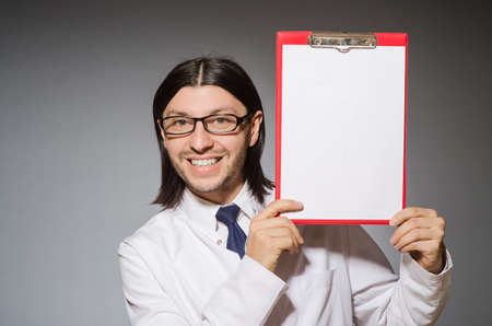 Male doctor with diary against gray