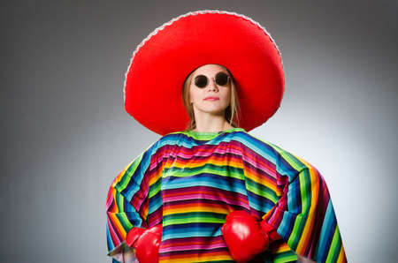 Girl in mexican vivid poncho and box gloves against grayの写真素材