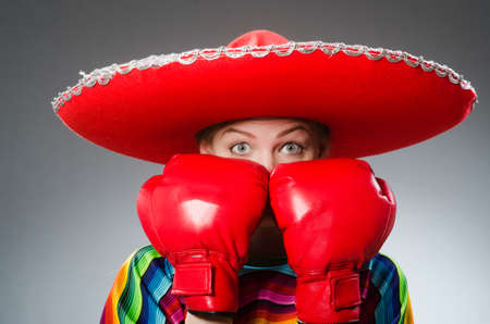 Girl in mexican vivid poncho and box gloves against grayの写真素材
