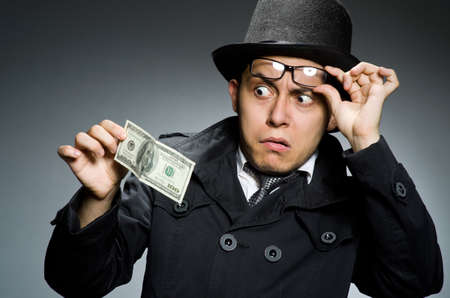 Young man in black coat holding money against grayの写真素材