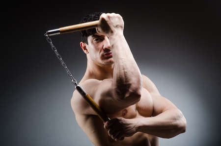 Muscular strong man with nunchucksの写真素材