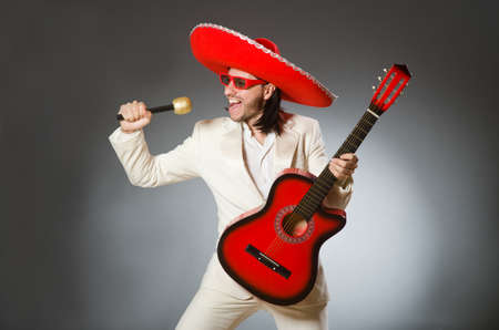 Funny mexican in suit holding guitar against grayの写真素材