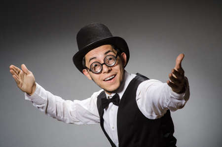 Young man in classical black vest and hat against gray