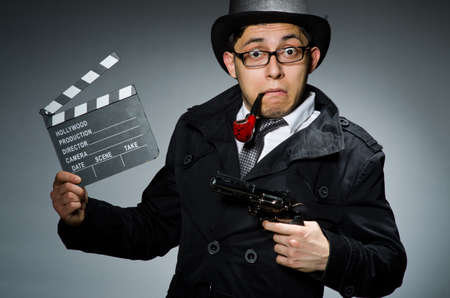 Detective in black coat with clapperboard against grayの写真素材
