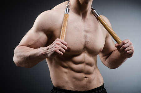 Muscular strong man with nunchucksの写真素材