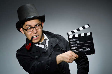 Detective in black coat with clapperboard against grayの写真素材