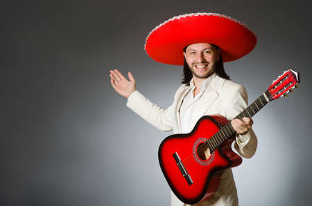 Funny mexican in suit holding guitar against grayの写真素材
