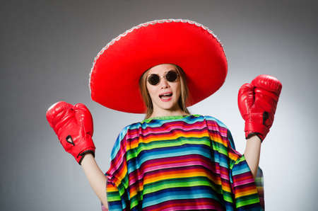 Girl in mexican vivid poncho and box gloves against grayの写真素材