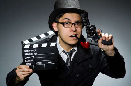 Detective in black coat with clapperboard against grayの写真素材