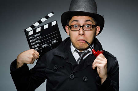 Detective in black coat with clapperboard against grayの写真素材