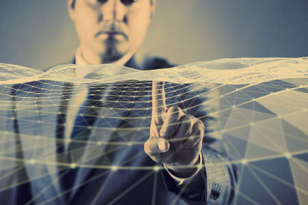 Businessman pressing virtual button in futuristic conceptの写真素材