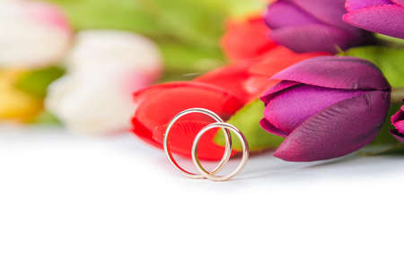 Wedding rings and flowers isolated on white backgroundの写真素材